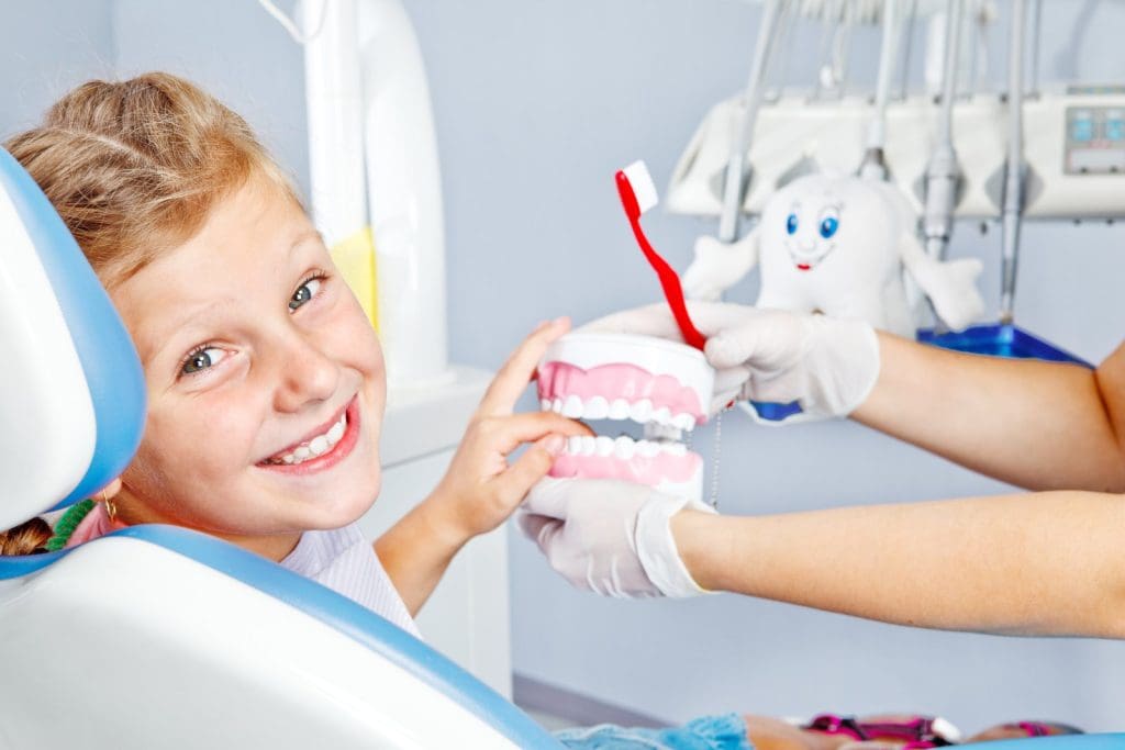 bác sĩ hướng dẫn vệ sinh răng miệng cho trẻ em tại phòng khám
